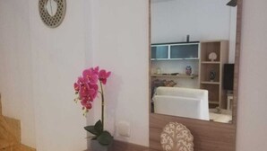 A bathroom with a wooden vanity, a mirror, a pink orchid, and a small decorative sailboat.