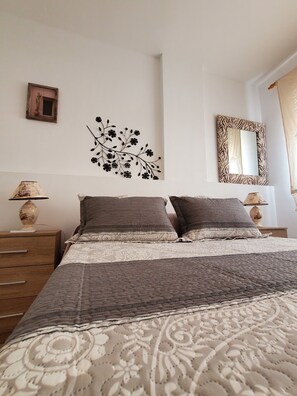A bedroom with a bed, two nightstands, a mirror, and wall art. - LUXURY SEMI-DETACHED HOUSE IN VERA PLAYA 200 M FROM THE SEA (Vera)