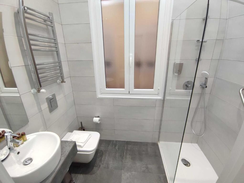 Un baño pequeño con lavamanos, inodoro y cabina de ducha de cristal.