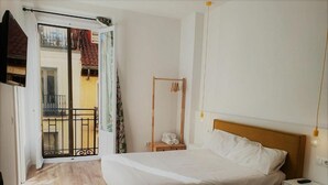 A bedroom with a bed, bedside table, and a hanging light fixture. - Hostal Manuela by gaiarooms (Madrid)