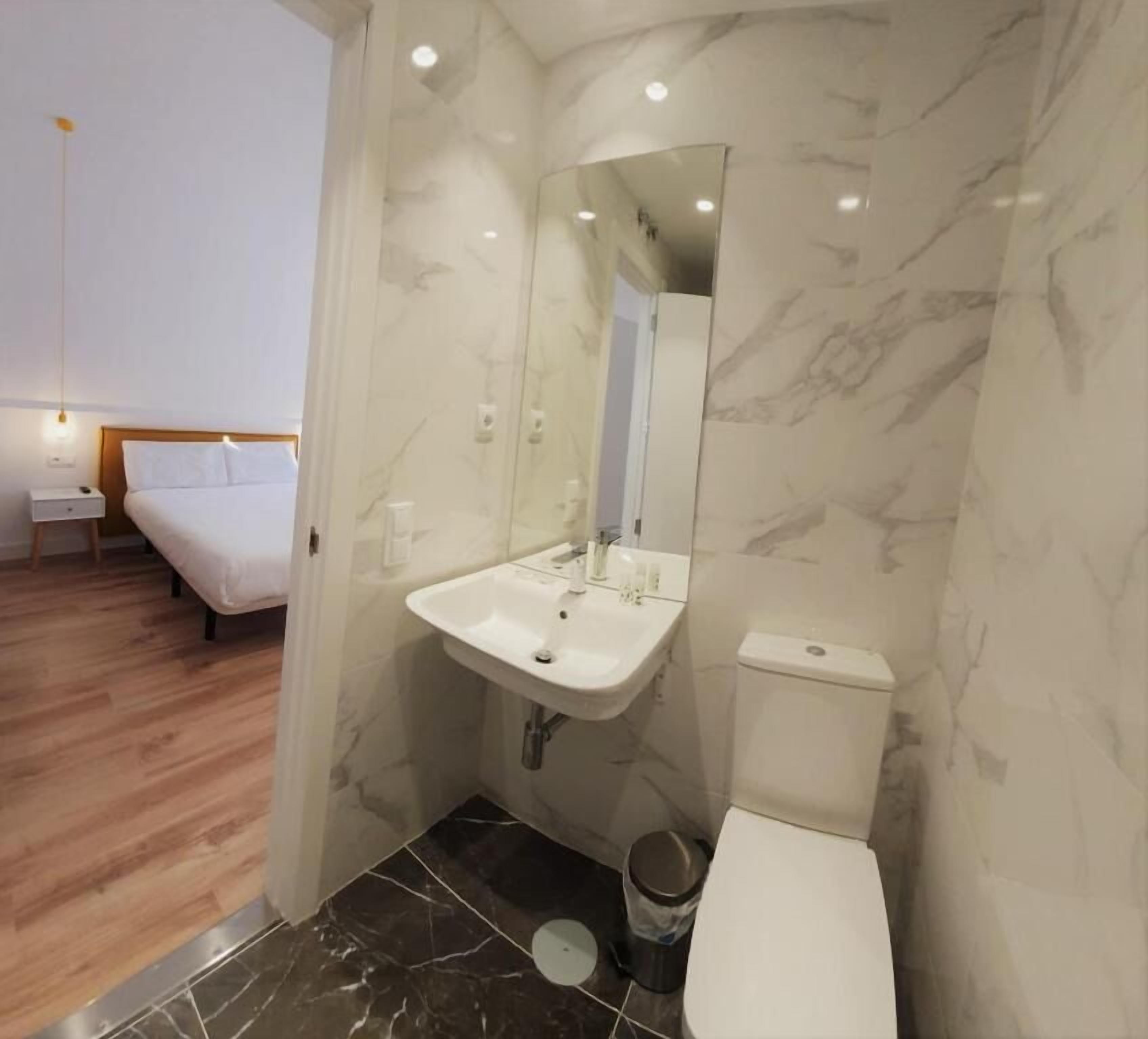 Ein modernes Badezimmer mit Marmorwaschbecken, Toilette und Spiegel.