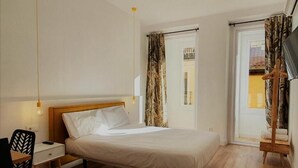 A bedroom with a bed, bedside table, chair, and a wardrobe. - Hostal Manuela by gaiarooms (Madrid)