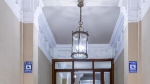 A grand hallway with marble flooring, a chandelier, and a staircase leading to a door. - Hostal Manuela by gaiarooms (Madrid)