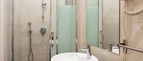 A modern bathroom with a glass-enclosed shower, a white sink, and a hairdryer mounted on the wall.