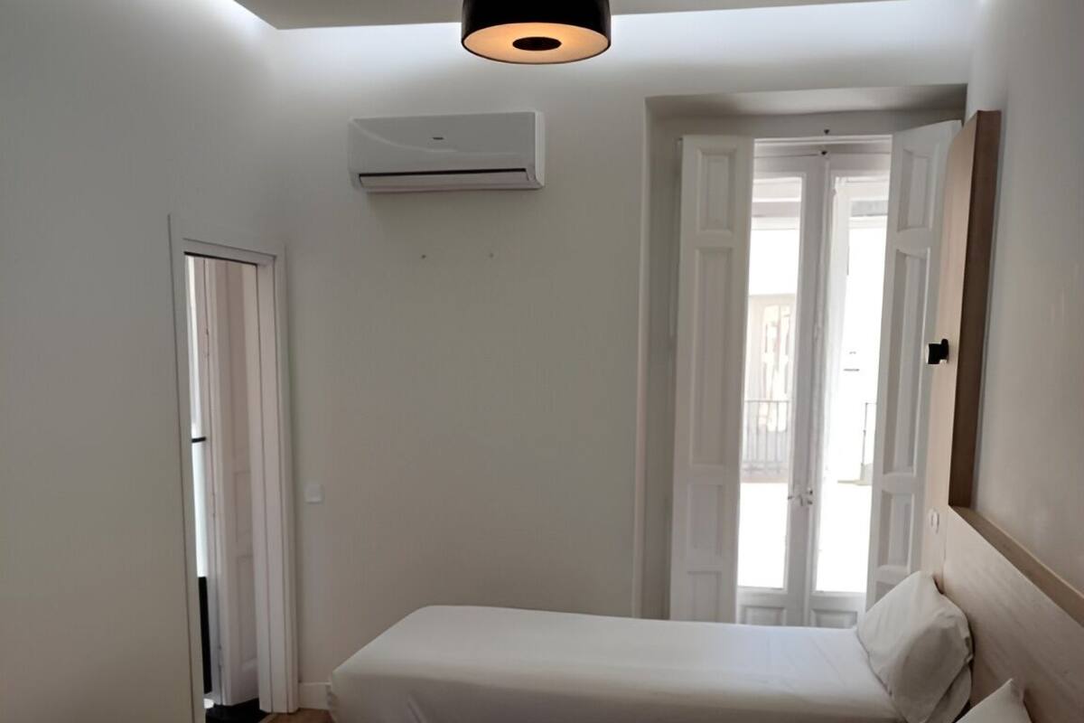 Een slaapkamer met twee bedden, een plafondlamp en een airconditioning.
