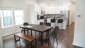 Une cuisine moderne avec des meubles blancs, un îlot central et un coin repas comprenant une table et des chaises.