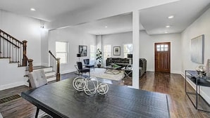 Un vaste espace de vie comprenant une table à manger en bois foncé, un escalier et un coin salon confortable avec un canapé et une table basse.