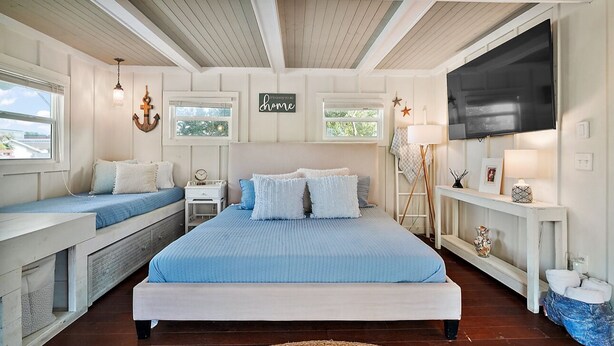 A bedroom with a large bed, a bench, a TV, and a window with a view.