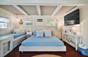 A bedroom with a large bed, a bench, a TV, and a window with a view.