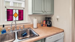 A kitchen with a double sink, a coffee maker, and a dish rack.