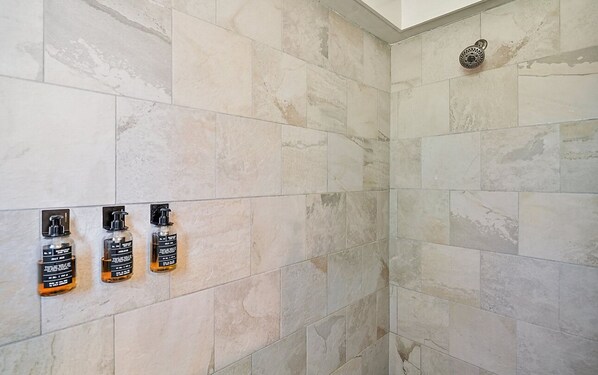 A shower area with beige tiles and a handheld showerhead.