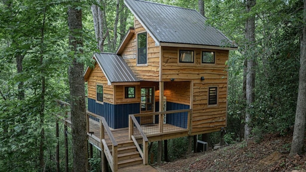 A wooden cabin with a balcony, surrounded by trees. - Secret Stash: Secluded Treehouse Overlooking Creek (Dahlonega)