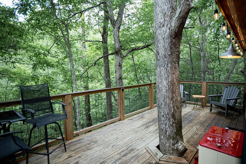 Une terrasse en bois avec des sièges d’extérieur, entourée d’arbres.