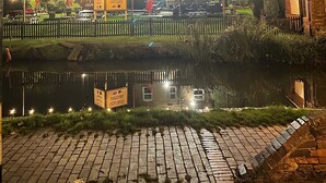 A two-story building with a lit signboard, a paved area in front, and a body of water reflecting the building. - Idyllic 2 bedroom Canal facing Cottage in Hopwas (Hopwas)