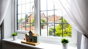 A window with white curtains, a small house model, and two potted plants on a windowsill. - Idyllic 2 bedroom Canal facing Cottage in Hopwas (Hopwas)