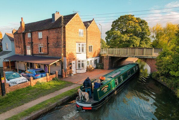 A narrow canal with a narrowboat docked at a brick house. - Idyllic 2 bedroom Canal facing Cottage in Hopwas (Hopwas)