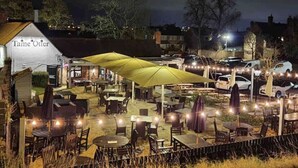 An outdoor dining area with tables and umbrellas, a building labeled "Tame Otter," and a parking lot in the background. - Idyllic 2 bedroom Canal facing Cottage in Hopwas (Hopwas)