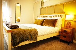 A neatly made bed with a headboard, a bedside table with a lamp, and a mirror on the wall. - Idyllic 2 bedroom Canal facing Cottage in Hopwas (Hopwas)