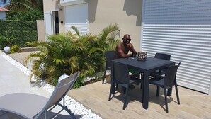 Eine Terrasse im Freien mit Tisch und Stühlen, umgeben von weißen Kieselsteinen und Pflanzen.