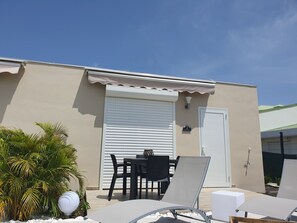 A rooftop patio with lounge chairs, a table, and a covered seating area.