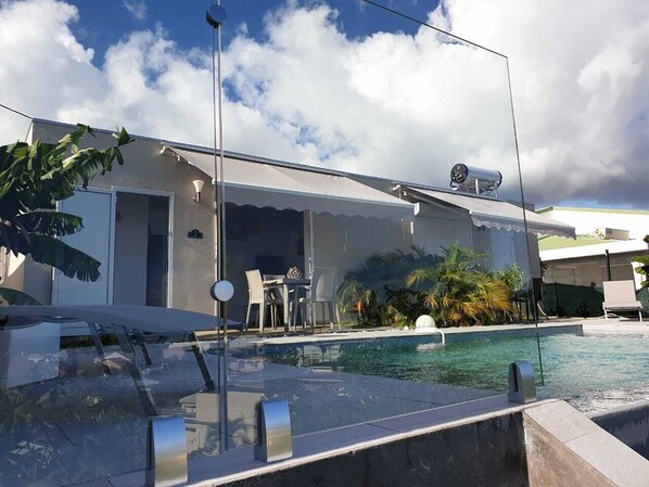 A modern house with a swimming pool, outdoor furniture, and a security camera.