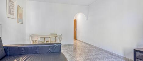 A spacious living area with a leather sofa, a wooden dining table, and chairs.