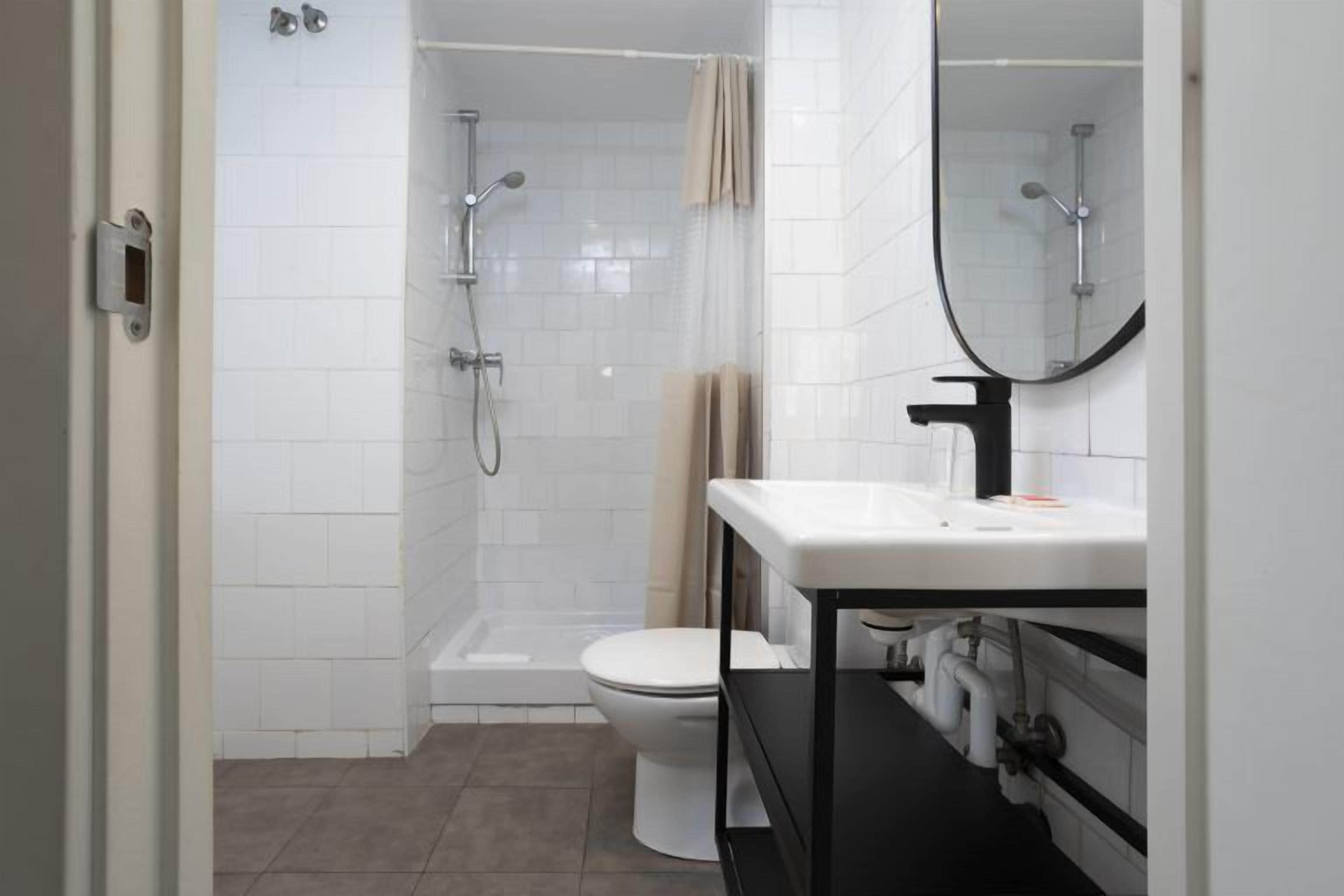 A modern bathroom with a shower, toilet, and sink.