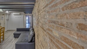 A modern interior with a brick wall, a grey sofa, and a wooden floor. - Hostal Bedmates (Barcelona)