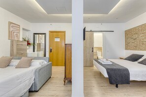 A modern hotel room with two beds, a wooden wardrobe, a mirror, and a brick wall.