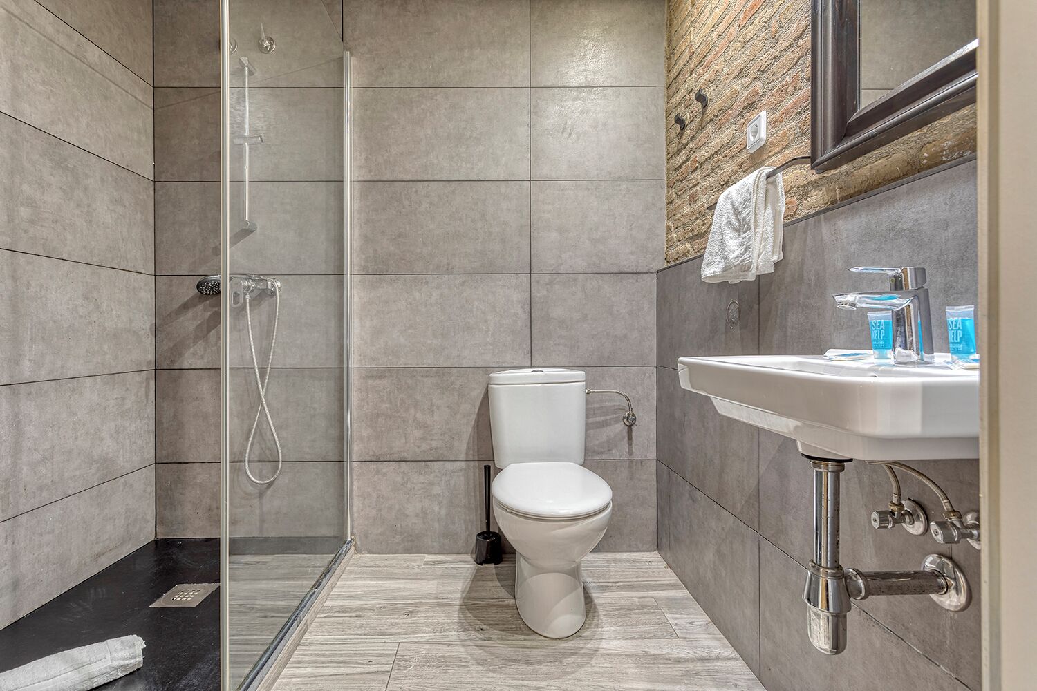 Une salle de bain moderne avec une douche à parois de verre, des toilettes blanches et un lavabo avec un miroir au-dessus.