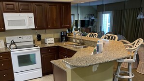 A modern kitchen with granite countertops, stainless steel appliances, and a central island with bar stools.