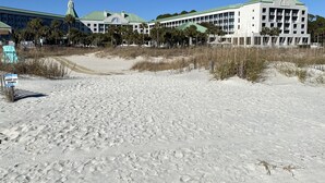 A beachfront hotel with multiple buildings, including a prominent structure with a green roof and a tower.
