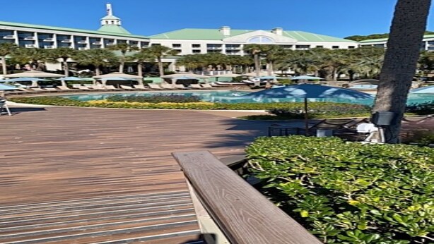 A resort with a pool area, wooden deck, and a large building with a green roof.