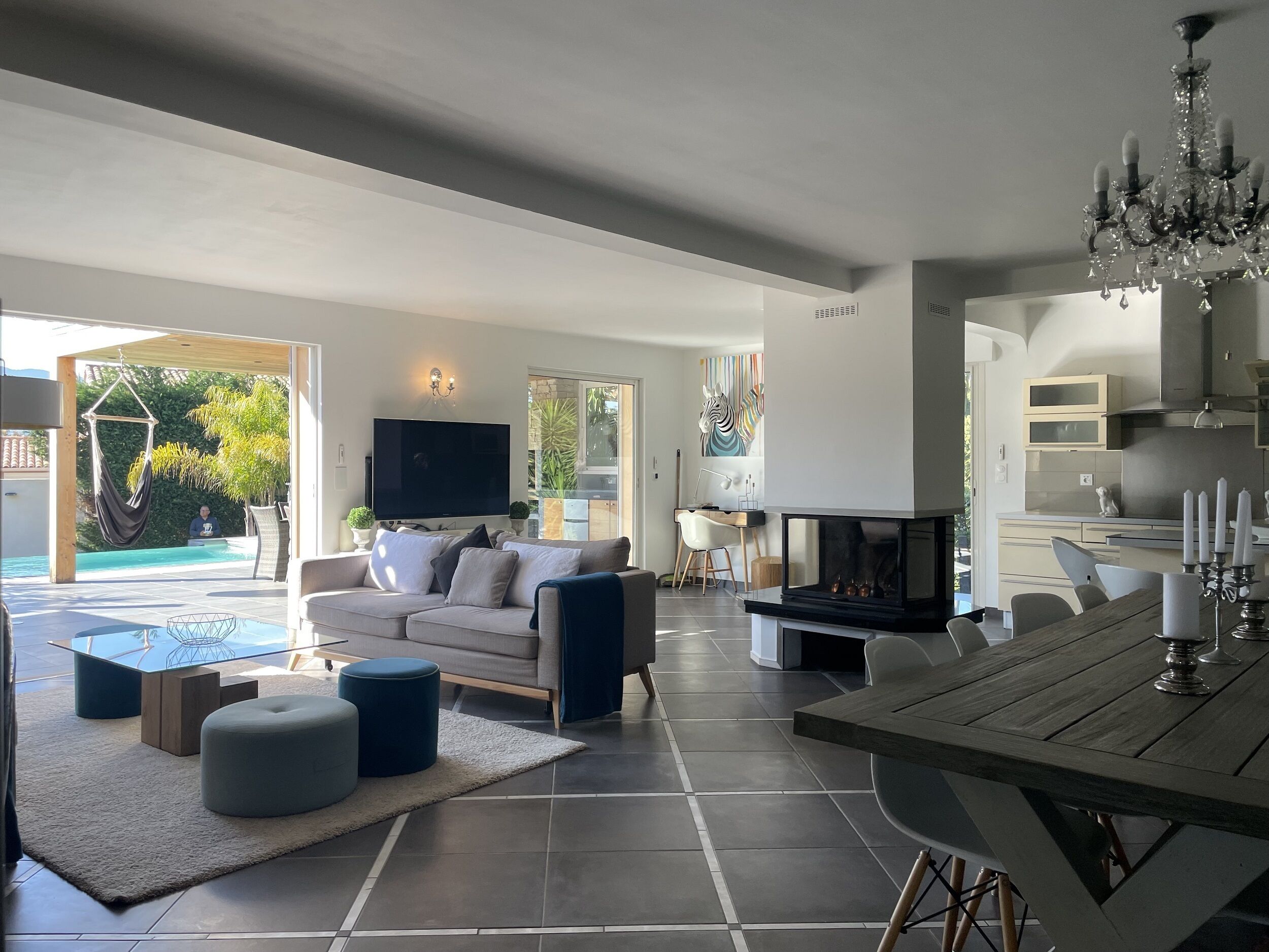 Een moderne woonkamer met een bank, poefs, een televisie en een open haard.