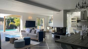 Een moderne woonkamer met een bank, poefs, een televisie en een open haard.