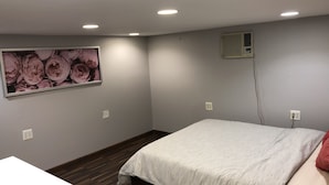 Ein Schlafzimmer mit einem Bett, einem Wandlüfter und einem Blumenbild.