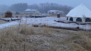 Een besneeerd landschap met een witte tent en meerdere gebouwen op de achtergrond.