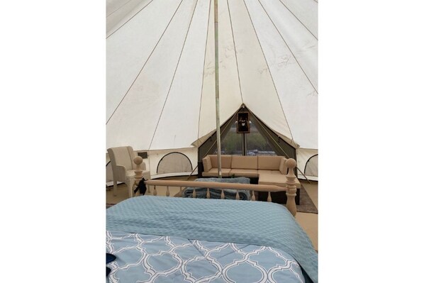 A tent with a bed, a small table, and a chair.