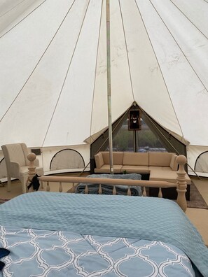 A tent with a bed, a sofa, and a chair inside.