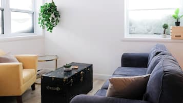A living room with a sofa, armchair, and a black suitcase on a small table.