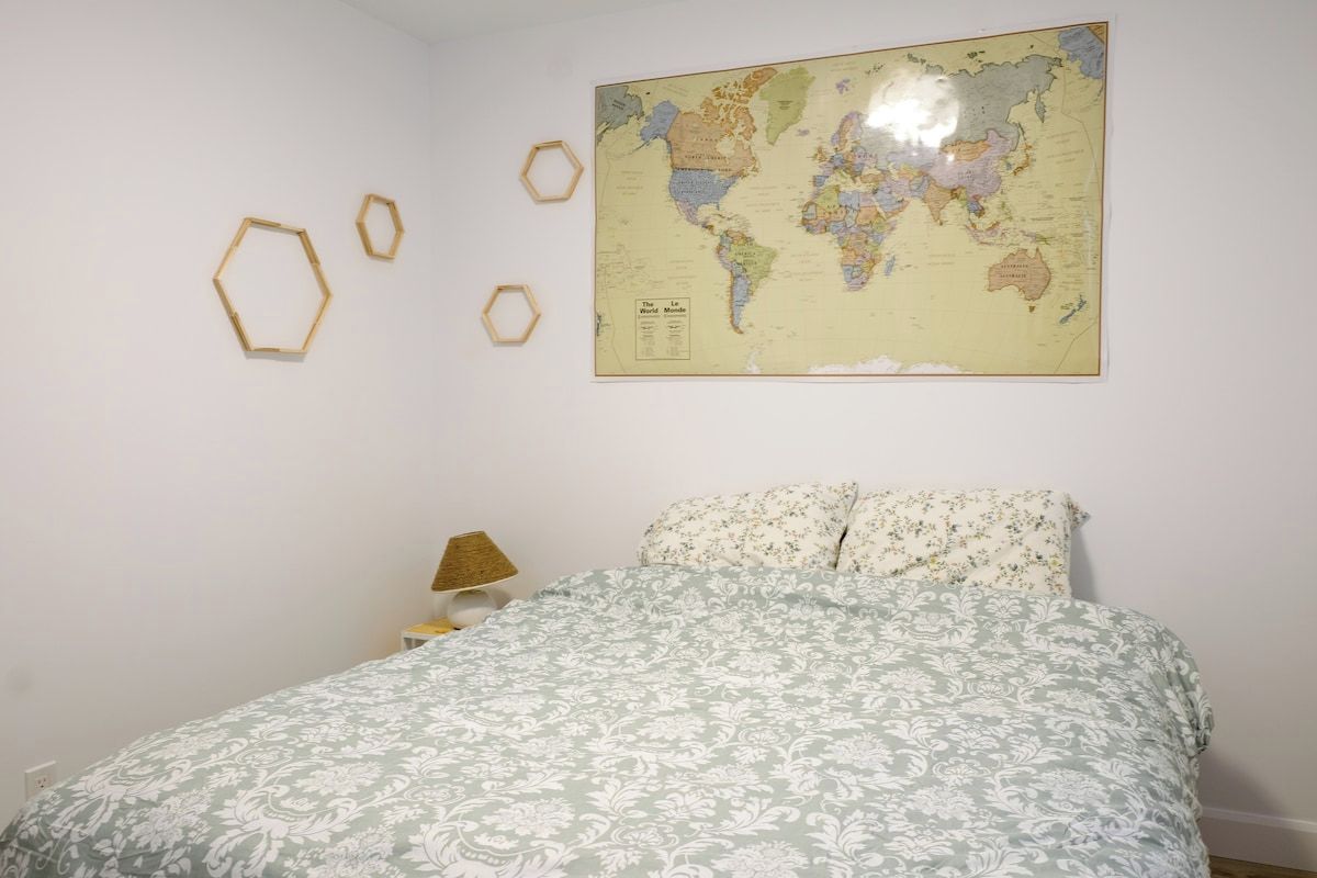 Un dormitorio con cama, un mapa mundial en la pared y decoraciones hexagonales.