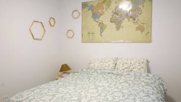 Un dormitorio con cama, un mapa mundial en la pared y decoraciones hexagonales.