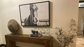 Una taula consola de fusta amb un llibre, una escultura, una fotografia de cavall amb marc i una planta en test.