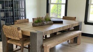 Taula de dinar de fusta amb caires de fibra, una banca i plantes decoratives.