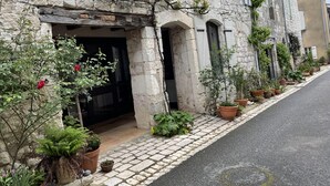 A stone building with a rustic entrance, potted plants, and a paved sidewalk. - Charming 4* gîte with private pool&jacuzzi 11 bedrooms/10 bathrooms (Touffailles)