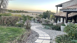 A garden pathway leading to a building with a tiled roof, surrounded by greenery and a view of fields. - Charming 4* gîte with private pool&jacuzzi 11 bedrooms/10 bathrooms (Touffailles)