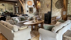 A spacious living area with a stone wall, a fireplace, and a dining area with a long table and chairs. - Charming 4* gîte with private pool&jacuzzi 11 bedrooms/10 bathrooms (Touffailles)