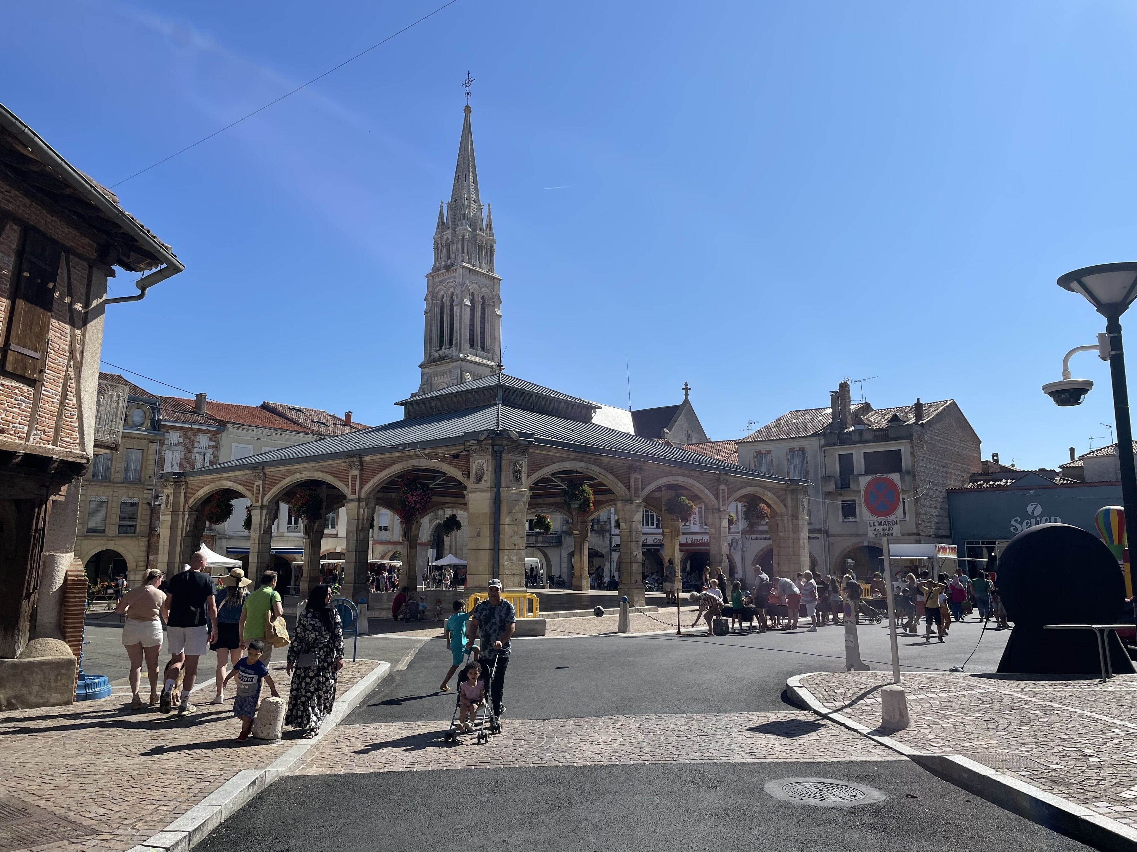 Un bâtiment historique doté d’une tour imposante, d’une galerie couverte et d’une rue pavée.