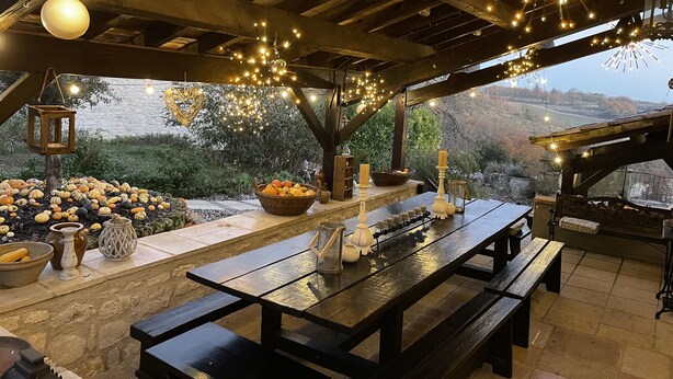 A rustic outdoor dining area with wooden benches and a long table, surrounded by a stone wall and a view of a hilly landscape. - Charming 4* gîte with private pool&jacuzzi 11 bedrooms/10 bathrooms (Touffailles)