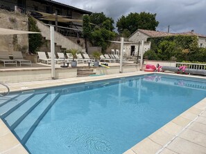 A swimming pool with lounge chairs and a stone building in the background. - Charming 4* gîte with private pool&jacuzzi 11 bedrooms/10 bathrooms (Touffailles)